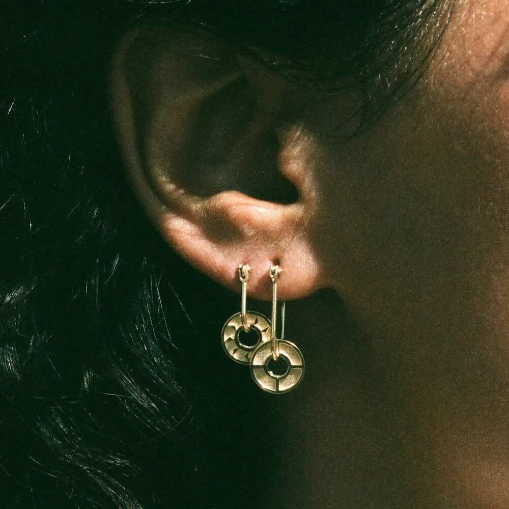 Model wearing Baby Ennead Earring in yellow gold