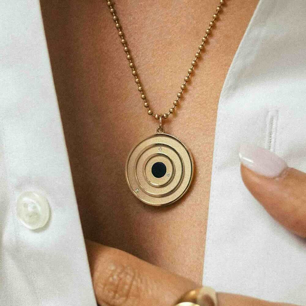 Model wearing Cosmos Pendant in yellow gold with onyx center stone and white diamonds