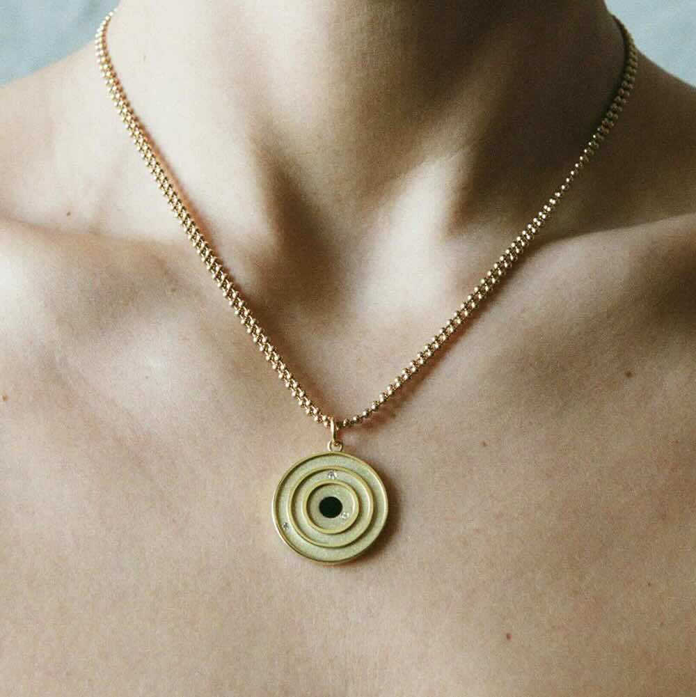 Model wearing Cosmos Pendant in yellow gold with onyx center stone and white diamonds