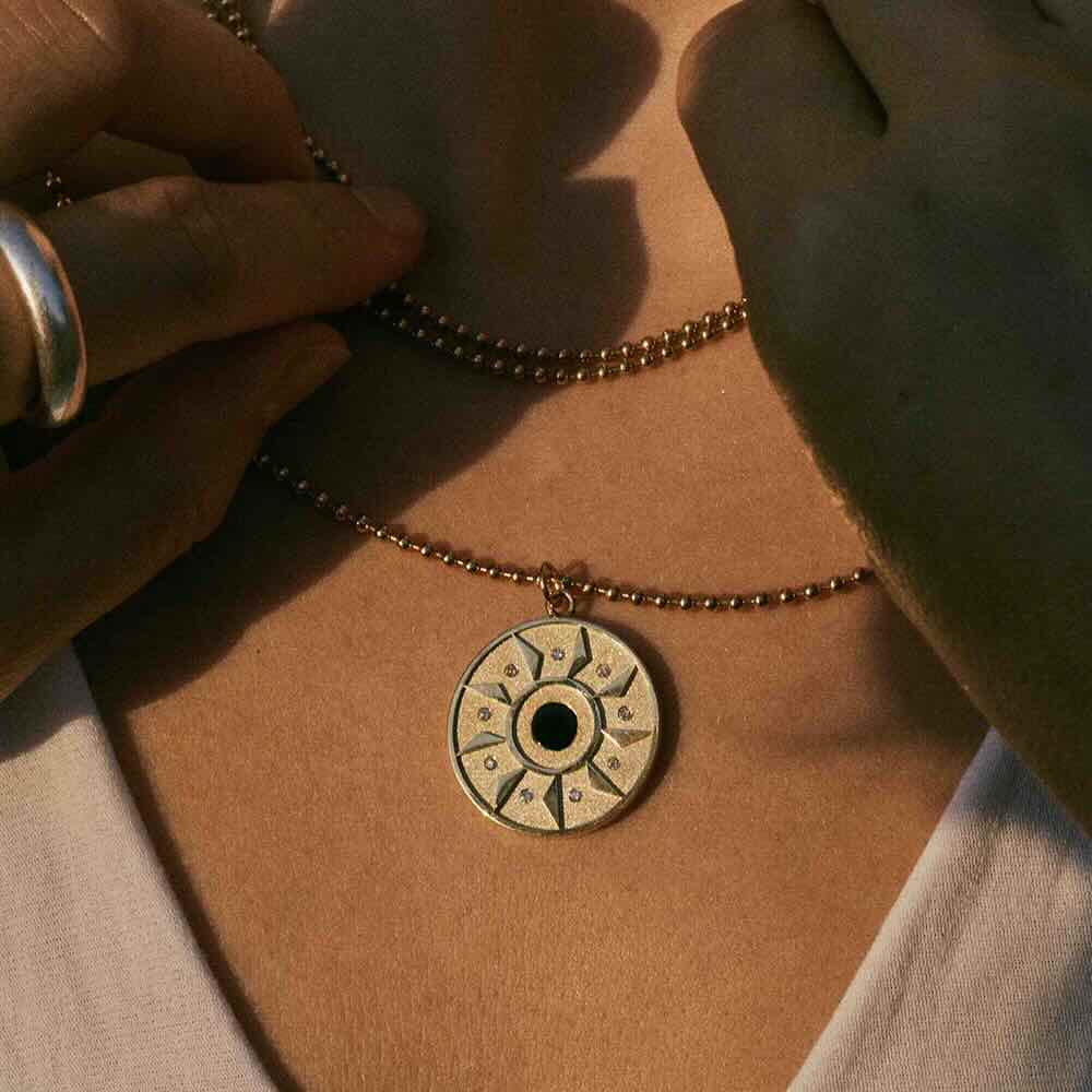 Model wearing Ennead Necklace in yellow gold with onyx center stone and white diamonds