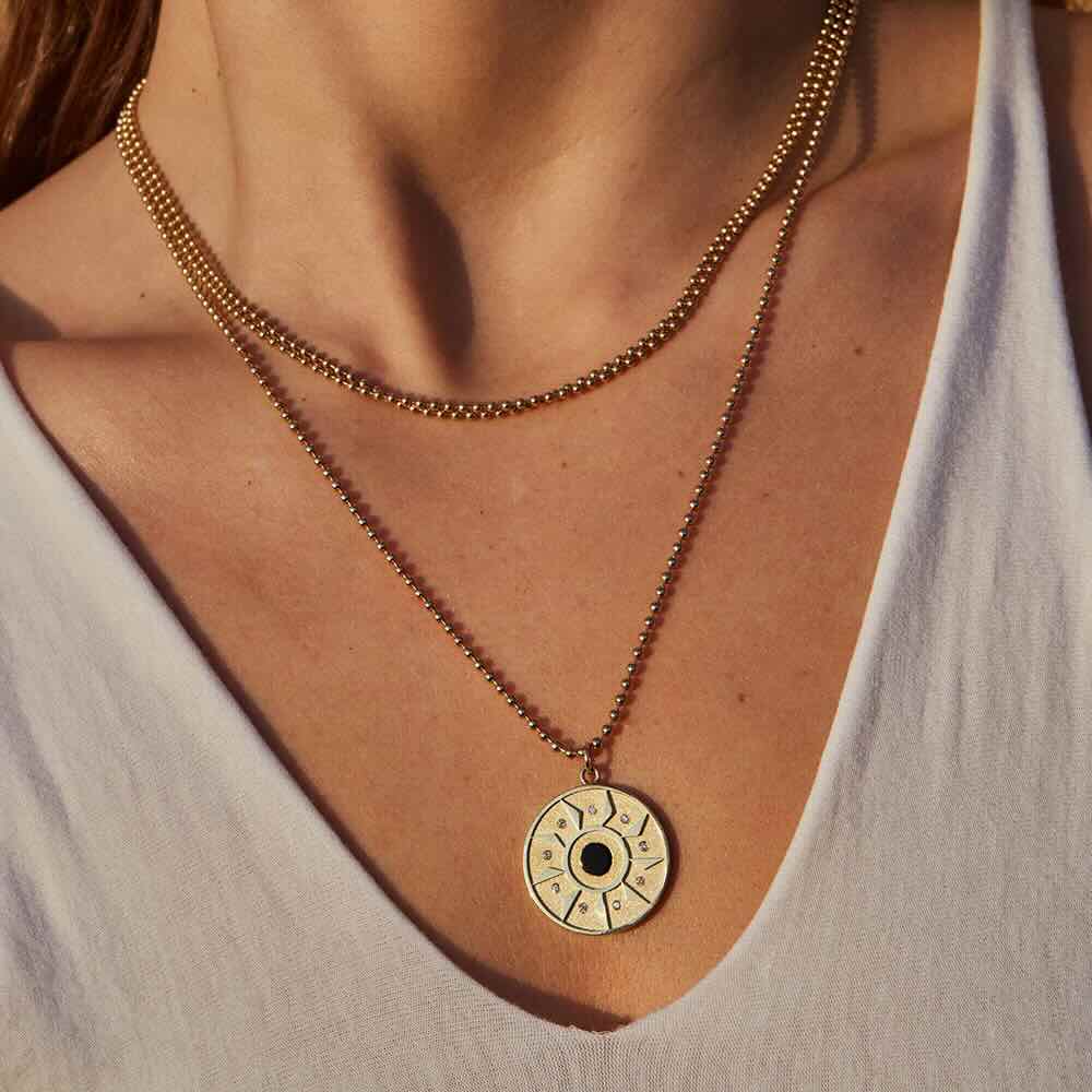 Model wearing Ennead Necklace in yellow gold with onyx center stone and white diamonds