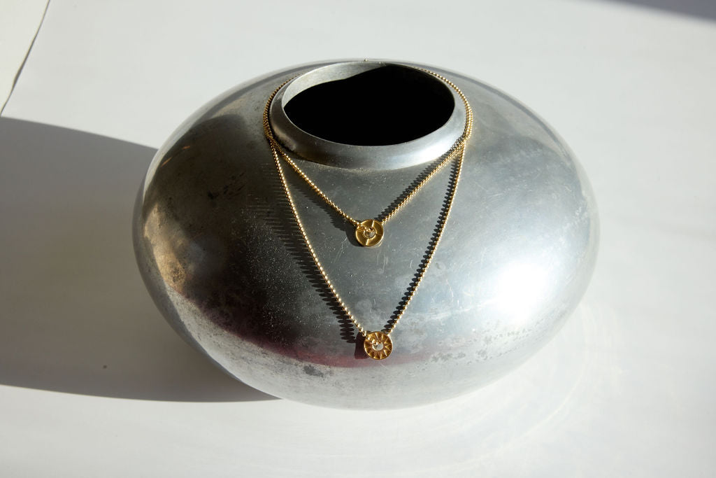 Gold necklaces displayed on a silver vase