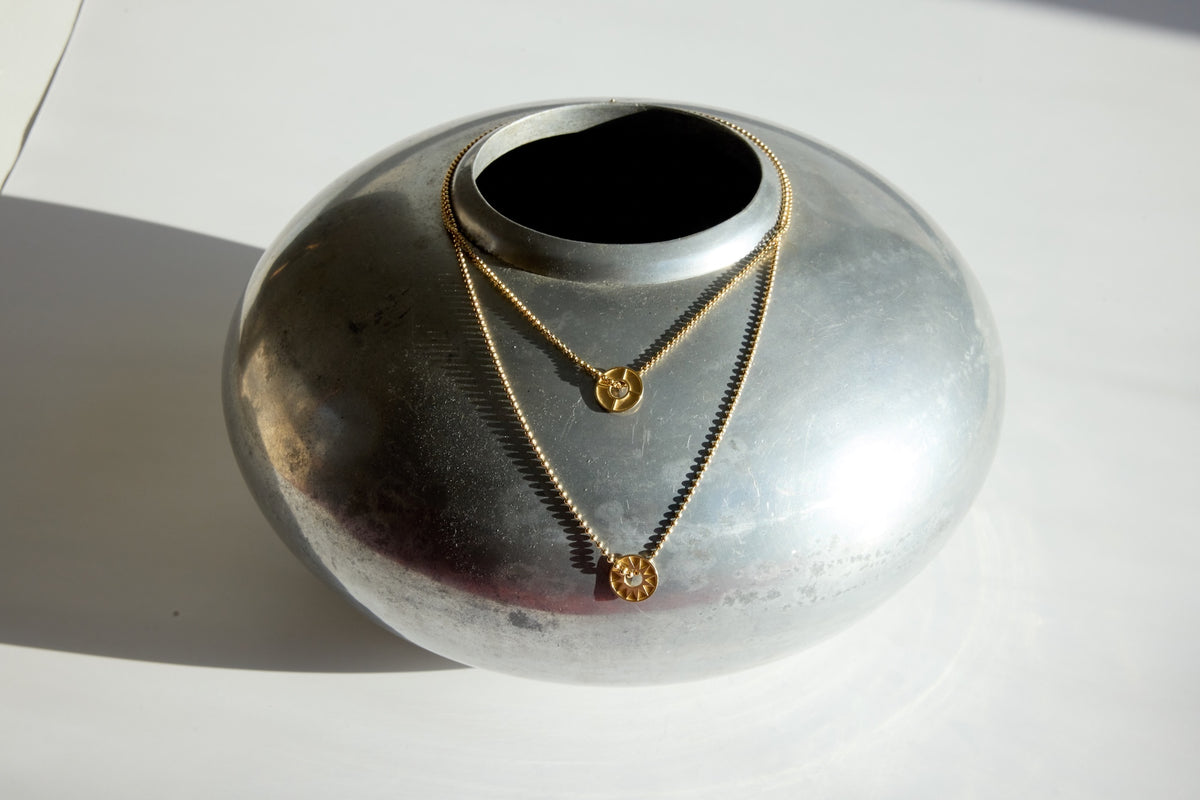 Gold necklaces displayed on a silver vase