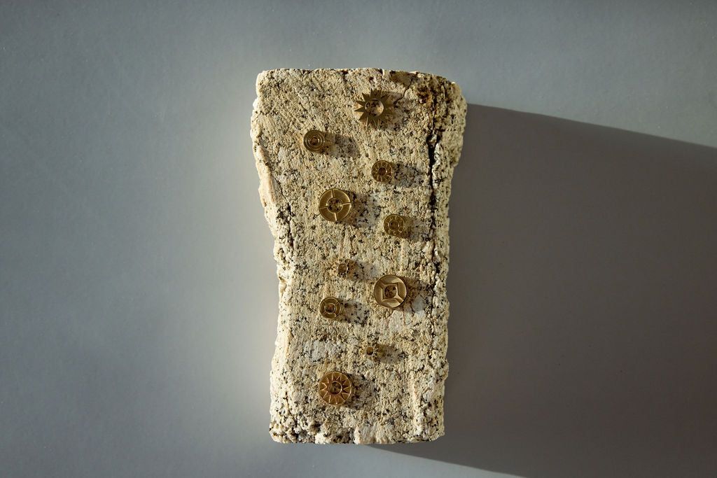 Gold symbolic jewelry pieces displayed on a textured stone block